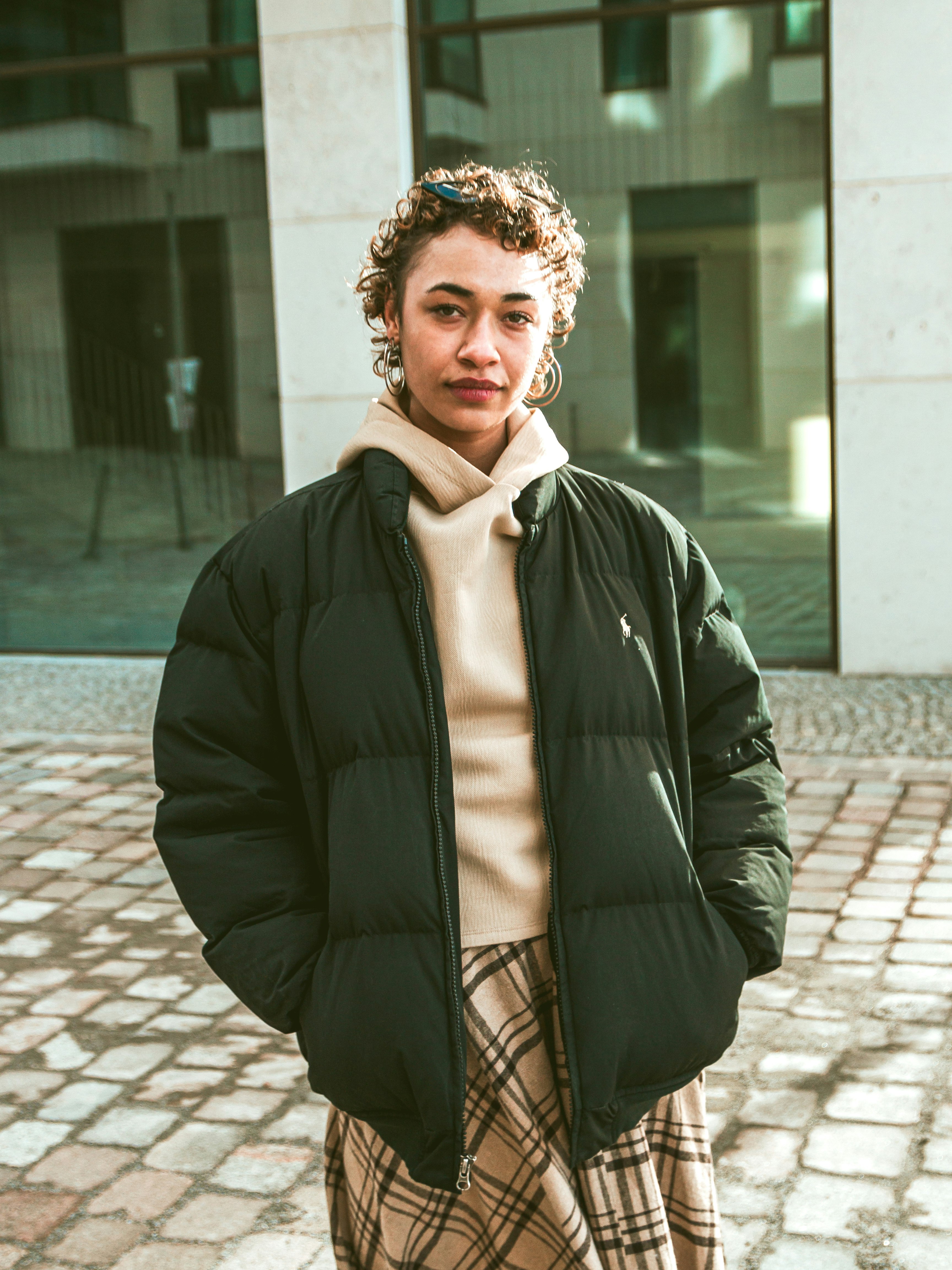 woman in black jacket standing on sidewalk during daytime